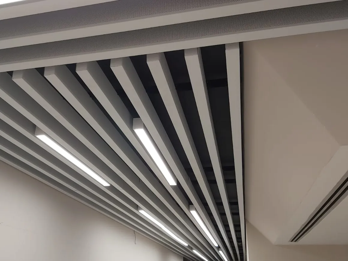 Close view of baffle blades with linear lights, next to a ceiling bulkhead with a slot diffuser