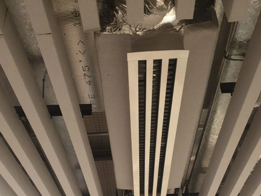 Baffle ceiling during installation, with a linear air diffuser set between the blades and insulated ductwork above