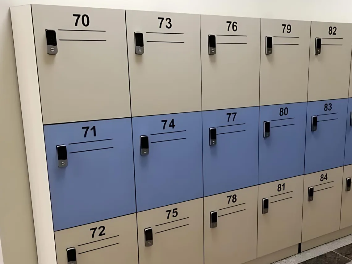 Close view of numbered beige and blue locker doors with battery keypad lock bodies