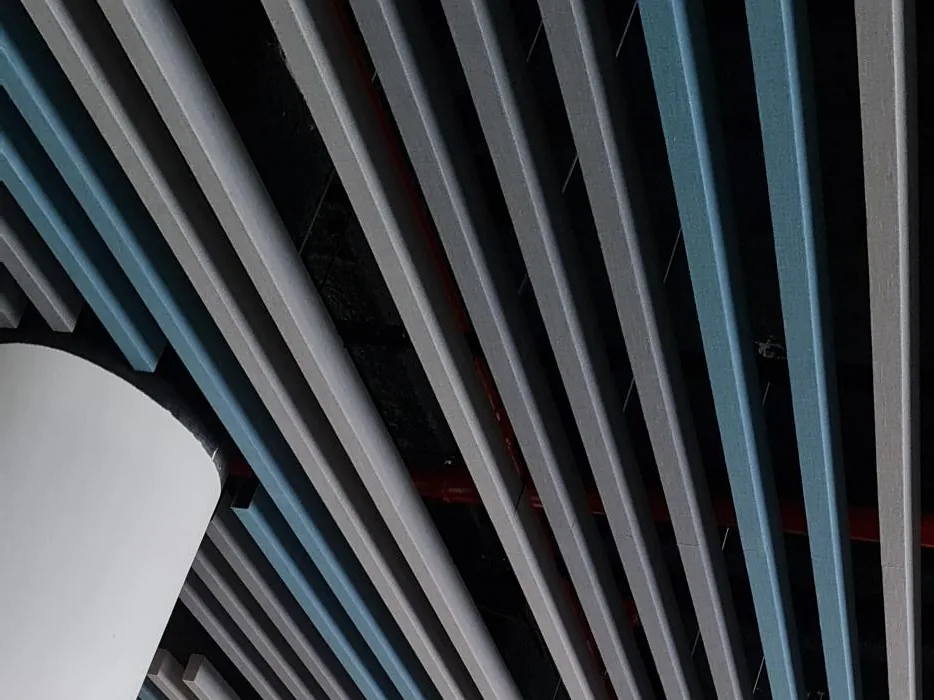 Grey and blue fabric-wrapped baffles running past a round white column under an open soffit
