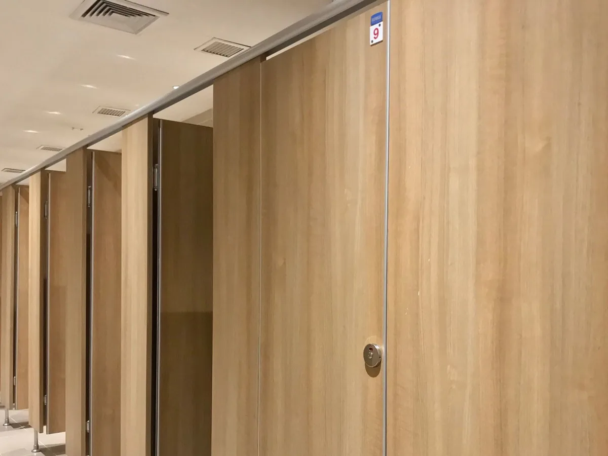 Washroom cubicles in a light-oak finish with numbered doors