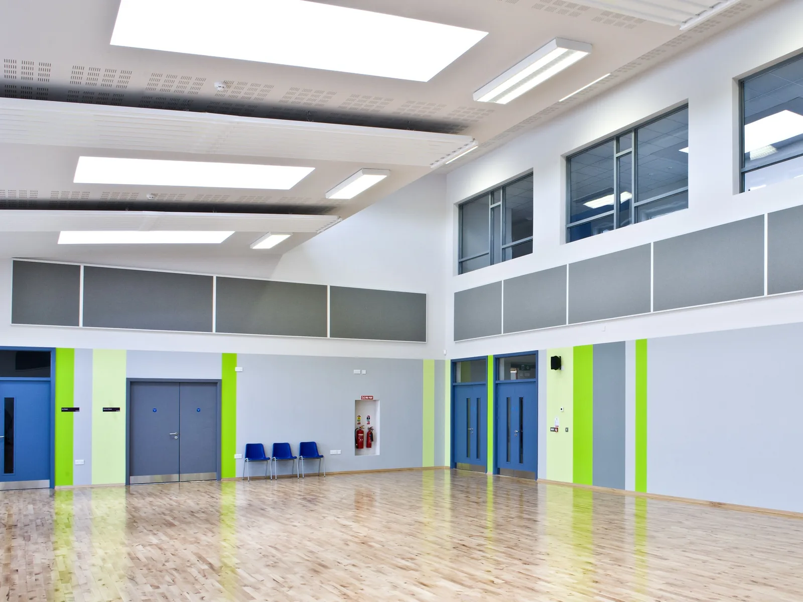 School hall with bands of grey fabric-wrapped acoustic panels along the upper walls, below high windows