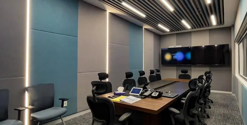 Meeting room lined with full-height fabric-wrapped acoustic wall panels in teal and grey