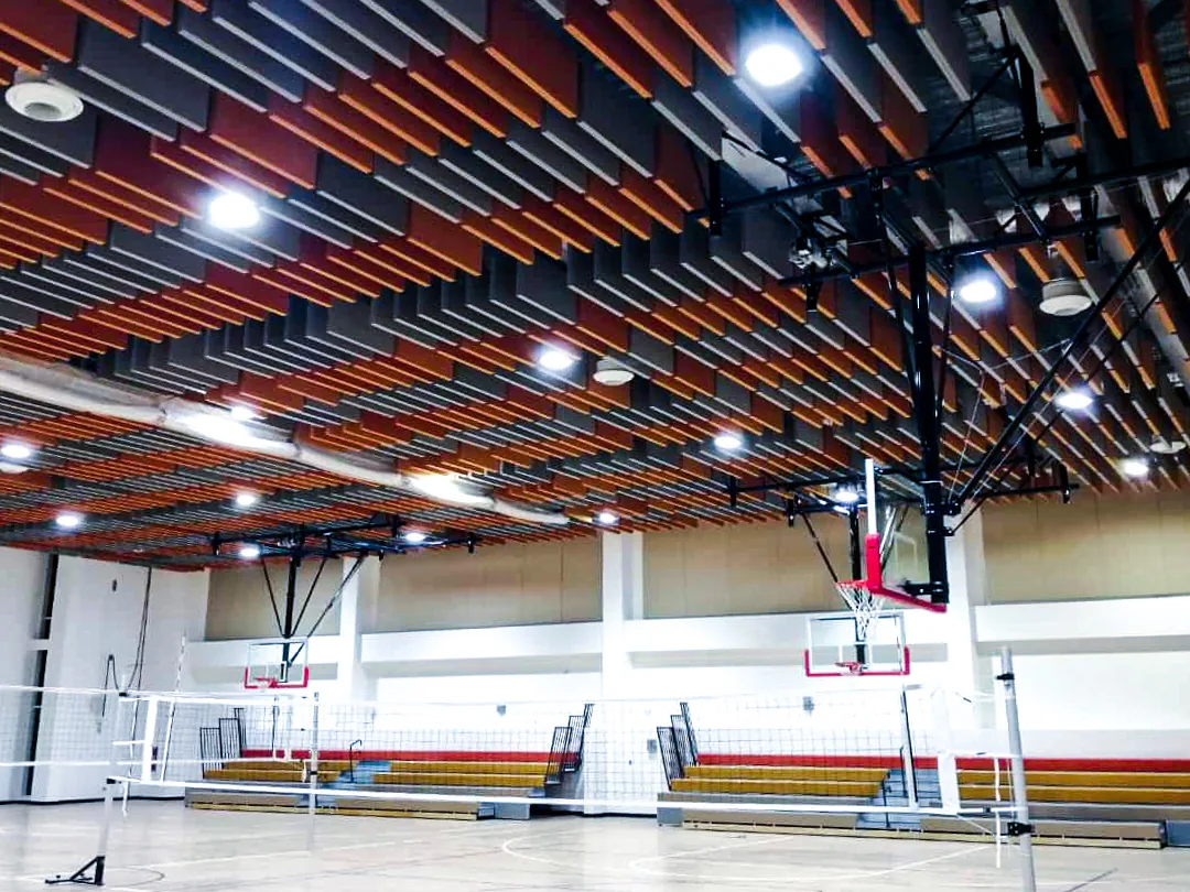 Sports hall with dense rows of orange and charcoal baffles over the court