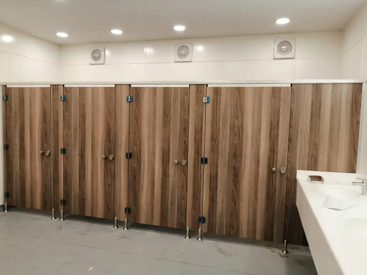 Installed toilet cubicles in a wood-grain decor on height-adjustable legs