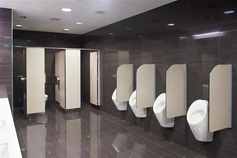Light-coloured toilet cubicles and matching urinal screens in a dark-tiled washroom